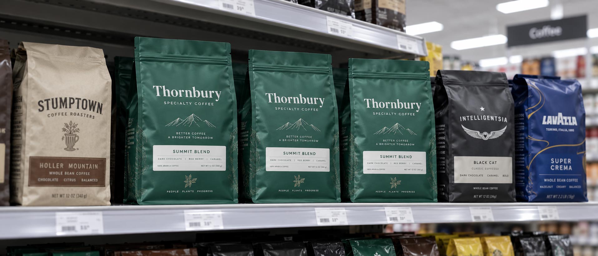 Coffee bags on a supermarket shelf under cool overhead retail lighting, the kind of light nobody approves artwork under