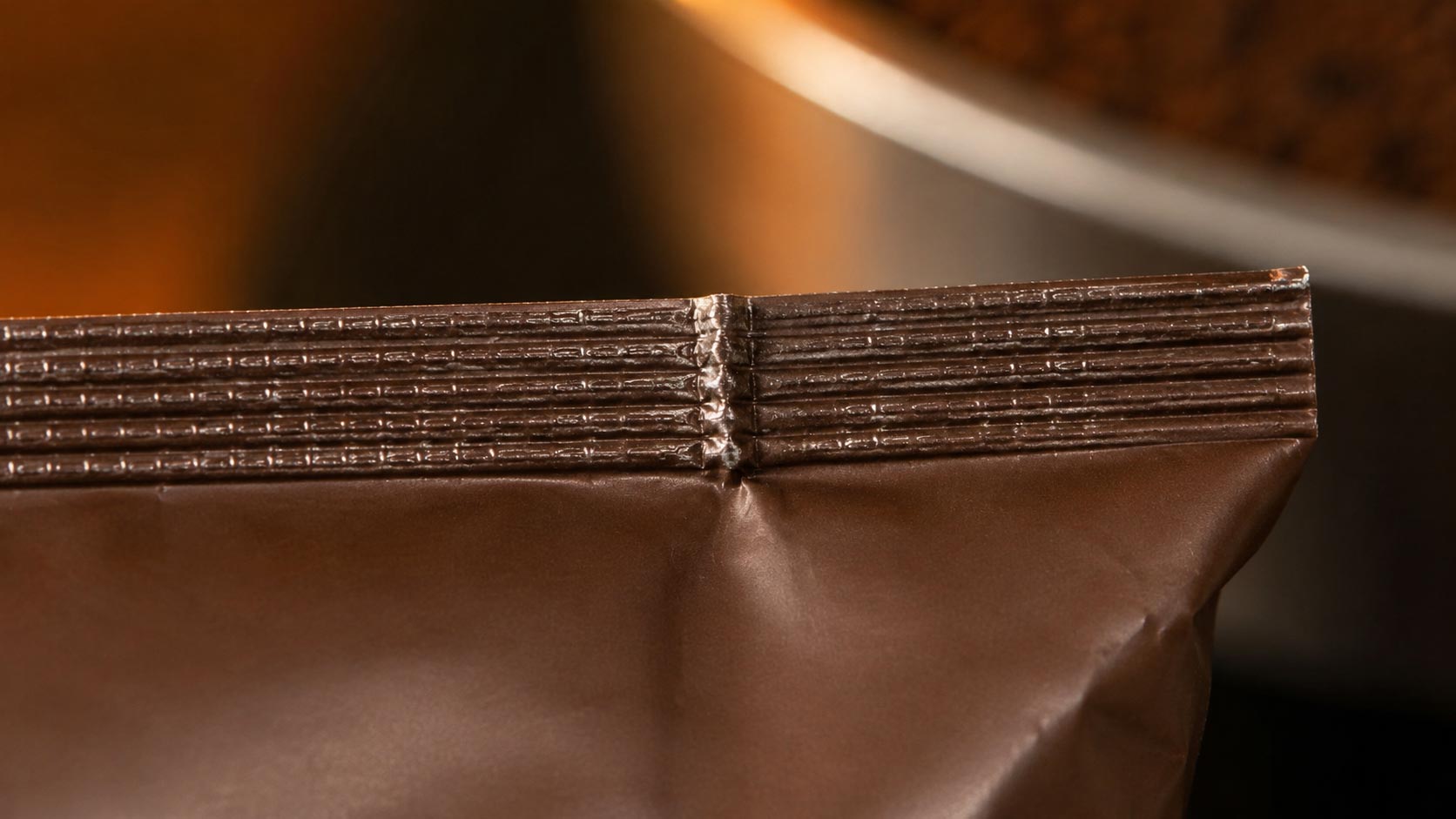 Close view of a coffee bag top seal showing a wrinkle folded into the seal area creating a channel